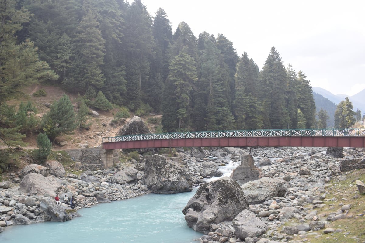 The Lidder River flowing through the scenic mountain valley of Pahalgam under blue skies