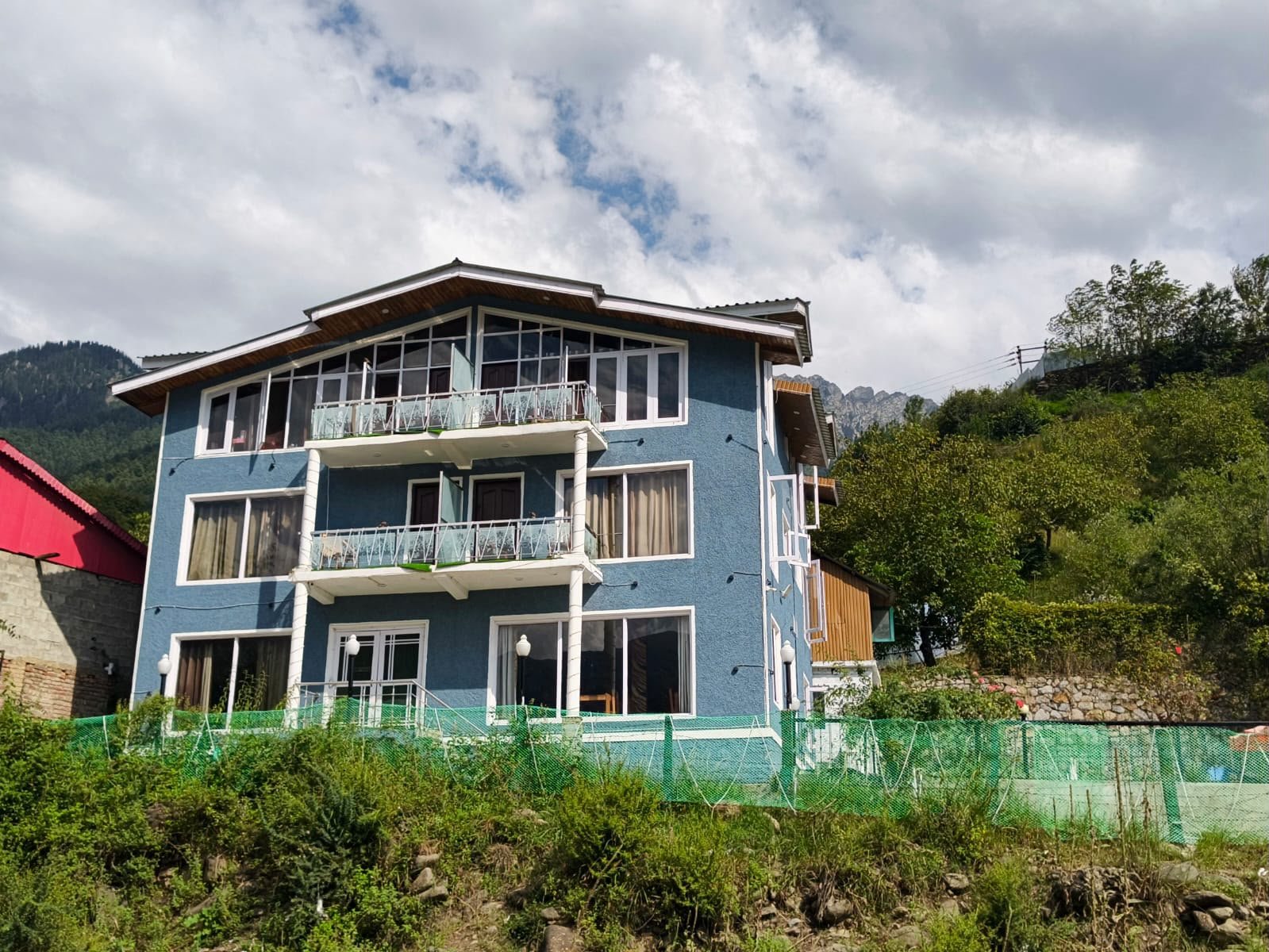 Hotel Rafting Heights building and pine-covered mountain backdrop in Pahalgam