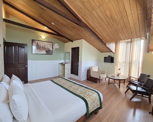 Spacious bedroom with sloped pine ceiling, king bed, and comfortable seating