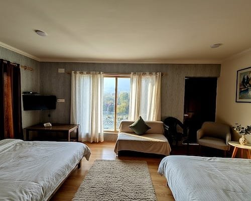 Guest room arranged with two comfortable beds and window seating bench